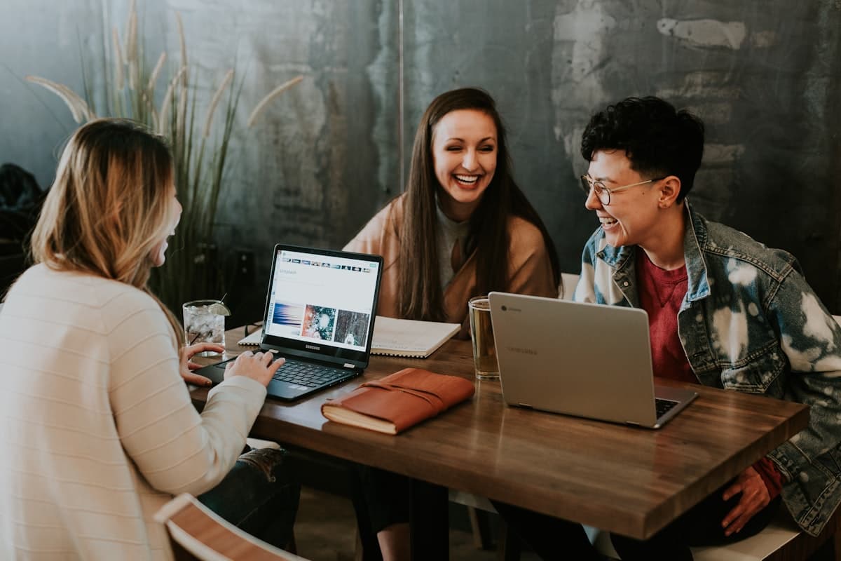 Trois personnes collaborent autour de leurs ordinateurs portables